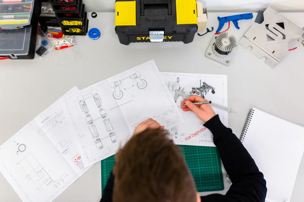 Engineer reviewing mechanical drawings at a workbench